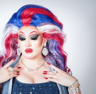elagant headshot of drag queen pensively looking down with a large red, white, and blue wig