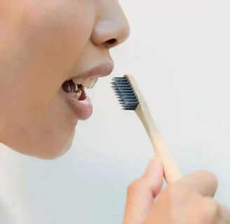 a woman in a bathrobear with a toothbrush in her mouth