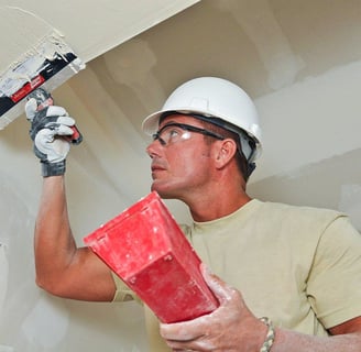 man using drywall knife to apply mud