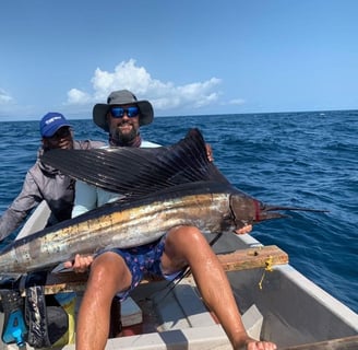big game fishing Zanzibar - a man holding a sailfish in a boat