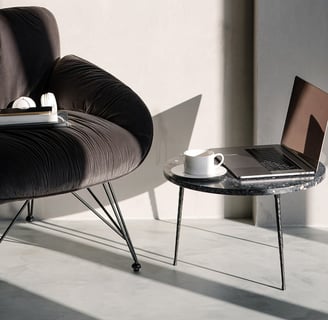 a laptop computer sitting on a table next to a chair with a smartphone on the seat