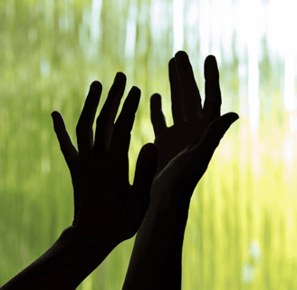 a person holding their hands up to a waterfall