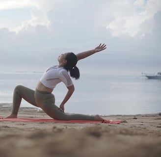 Woman stretching on a beach at sunrise, practicing active recovery with yoga to promote muscle flex