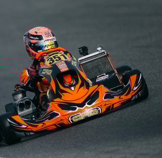 Pilote de karting en tenue orange sur le kart numéro 351 en pleine course.