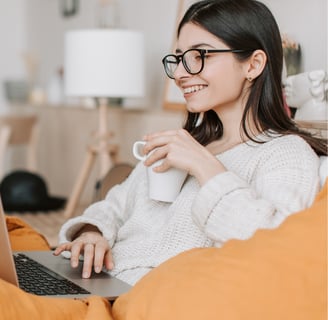 a woman sitting on a couch with a laptop and a cup of tea