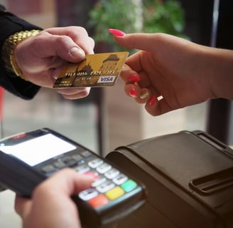 Person handing a gold Visa credit card to another person for payment at a terminal.