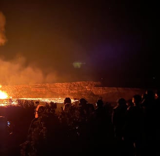 a group of people standing at edge of Halema'uma'u Crater watching eruption fountain