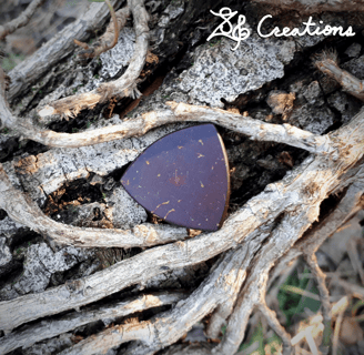 One of our Pythagorean coconut shell guitar picks on top of a vine encrusted branch.