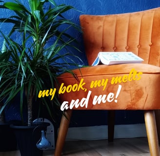 Cayla Henri: a chair with a book and a plant in front of a blue wall