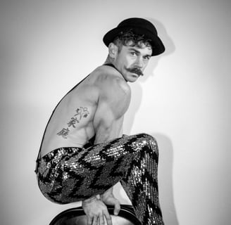 Black and white portrait of muscular circus performer suspended over chairs with shiny pants