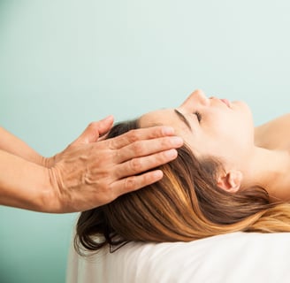 uma terapeuta impondo as mãos sobre a cabeça de uma mulher para a terapia reiki