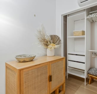 a closet with a shelf of clothes and a basket of flowers