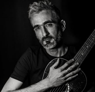 un homme tient une guitare dans ses bras et regarde l'objectif