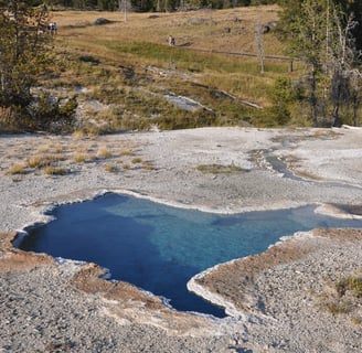 a large geothermal blue pool in yellowstone national park