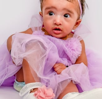 a baby girl in a purple dress and white shoes