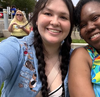 two women sitting next to each other in front of a crowd smiling