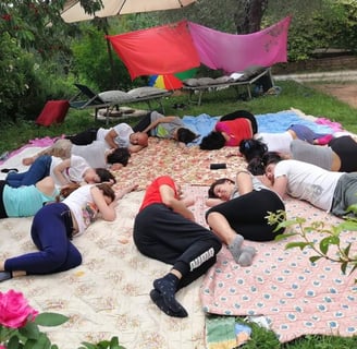 a group of people sitting on a blanket on a blanket, rilassamento, classe bioenergetica