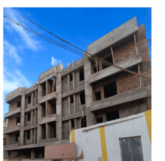 A multi-story residential building under construction, with exposed brick walls and concrete beams.