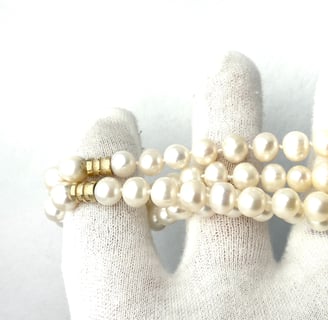 a woman's hand holding a bracelet with a gold coin