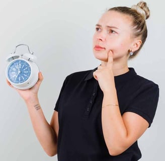 a woman holding a clock and looking at the time and thinking something