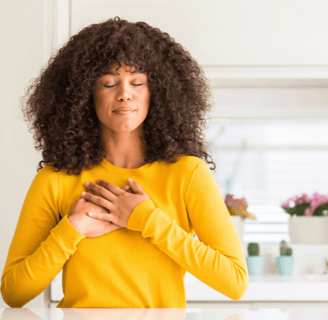 a lovely young black woman expressing gratitude with her hands on her heart