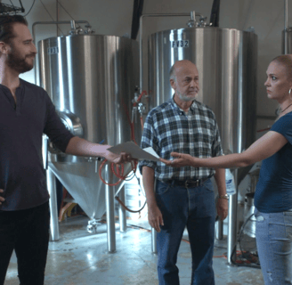 two men and woman standing in a brewery