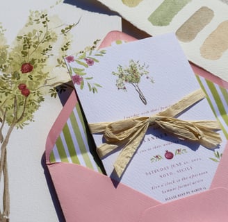 close up of wedding invitation inside envelope with original pomegranate tree artwork in the back