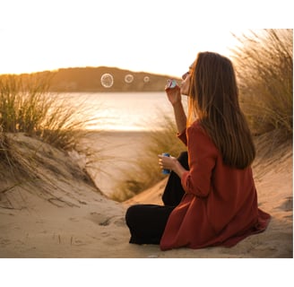a woman blowing bubbles in the sand