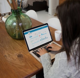 a woman sitting at a table with a laptop computer displaying Xero software