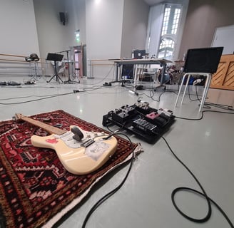 une guitare électrique et un pedalboard, avec pédales d'effets et ampli installés pour un atelier