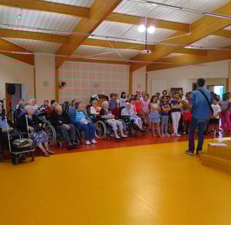Un musicien fait chanter une chorale composée de personnes âgées et d'enfants