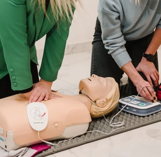 Two women administering CPR training on a CPR dummy in a training