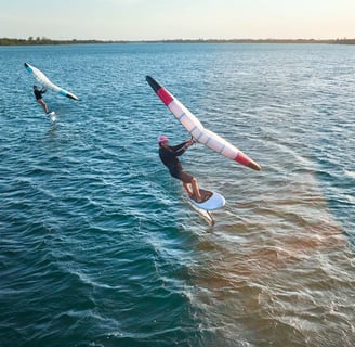 Saulėlydis Svencelėje su wing foil sportininku virš vandens paviršiaus
