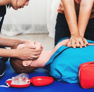 Two people practising CPR on a dummy in First Aid training