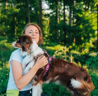 Toni hält Hund im Arm auf Baumstamm – achtsamer Moment im Waldbaden bei Takoda