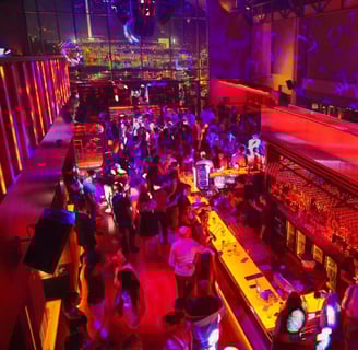a crowded bar with people sitting at tables and drinking