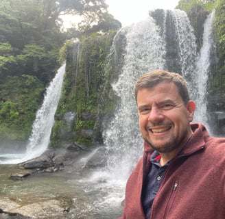 Picture of the site owner standing in front of a waterfall in Japan