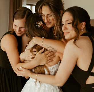 Four emotional bridesmaids embracing the bride.