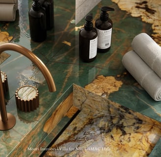 Close-up of a Green marble countertop with gold faucet and accessories in a modern bathroom.