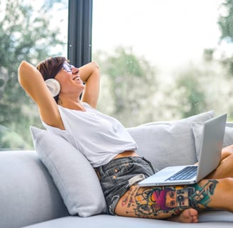 a woman sitting on a couch with her laptop. She is practicing English with music