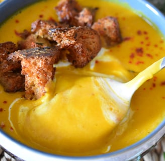 a person holding a spoon and in a bowl of soup