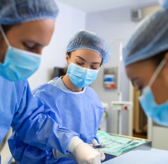 Three surgeons in blue scrubs and masks are focused on a surgical operation in operating room