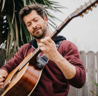 a man playing a guitar and singing into a microphone