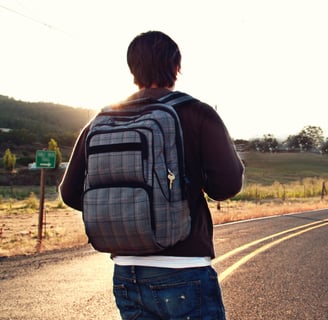 Ein alleinreisender Mann mit Rucksack auf einer Straße