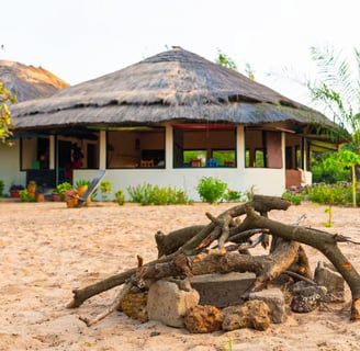 A peaceful image of Tamba Kuruba Eco-Lodge in Kartong, nestled amidst lush greenery and tall trees. 