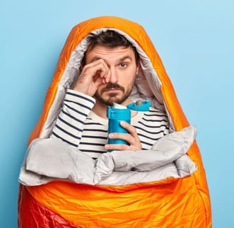 a man in a sleeping bag with a coffee flask