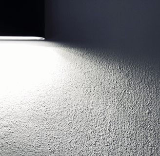 Textured home interior wall lit by spotlight, suitable for illustrating hidden damages assessed during insurance claims.