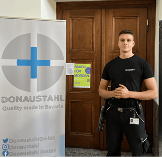 Eine Sicherheitskraft in "SECURITY"- Shirt vor einer Tür