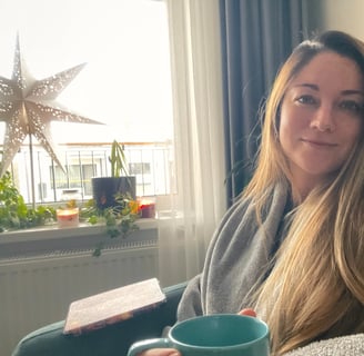 A picture of Christy sitting in her office with a cup of coffee and a warm welcoming attitude.
