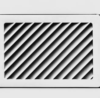 Angled black slats inside a white rectangular vent.